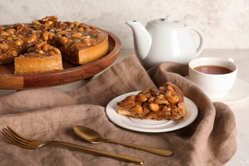 Wooden board and plate of cut sweet tart with different nuts and caramel on white background