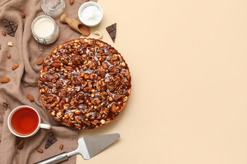 Sweet tart with different nuts and cup of tea on beige background