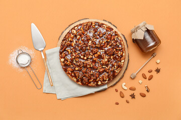 Wooden board of sweet tart with different nuts and caramel on brown background