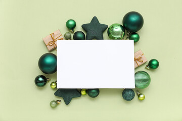 Blank card, Christmas balls and gift boxes on green background