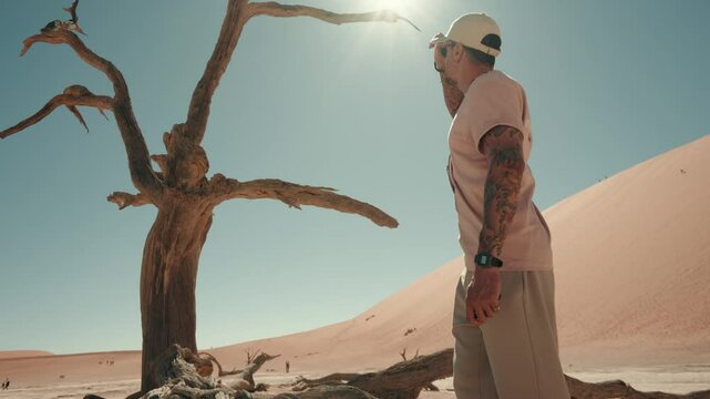 One man walking in the Deadvlei salt pan with a giant dune in the backdrop. Sossuvlei, Namibia