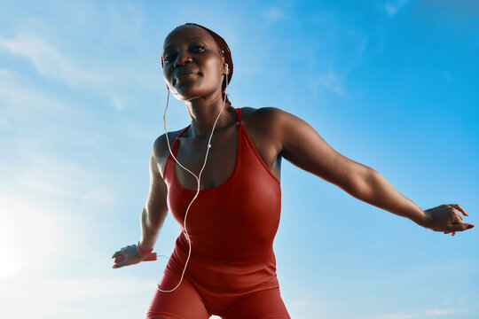 Young woman exercising outdoors in a red outfit against a blue sky - Powered by Adobe