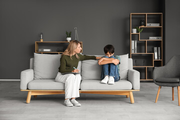 Female psychologist with upset teenage boy sitting on sofa in office © Pixel-Shot