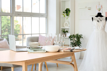 Wedding planner's workplace with laptop and tableware in office