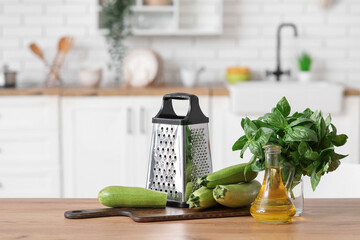 Grater with vegetables and oil on table in kitchen