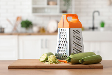 Grater with zucchini on table in kitchen