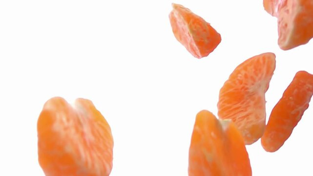 Peeled tangerine pieces are falling and rotating on the white background in slow motion. High quality 4k footage