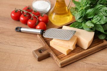 Cutting board with cheese and grater on table in kitchen