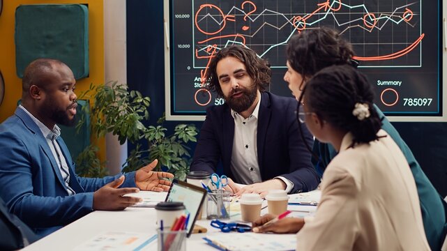Startup team evaluating infographics data in an executive meeting, corporate restructuring or organizational changes. Adapting the organization to evolving market conditions. Camera A.