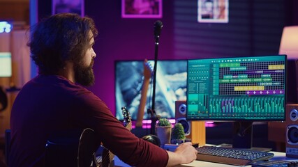 Music producer operating with electronic setup of home studio, recording acoustic guitar sounds....