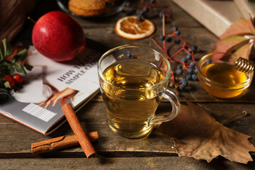 Autumn composition with cup of green tea, cinnamon sticks and leaves on wooden background, closeup