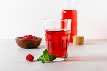 Raspberry drink in the glass on the light background.