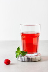 Raspberry drink in the glass on the light background.