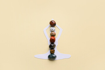 Set of chakra stones and paper figure of meditating human on beige background