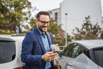 Adult businessman stand in the parking lot and use mobile phone © Miljan Živković