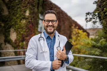 Portrait of adult man doctor stand with clipboard on the terrace