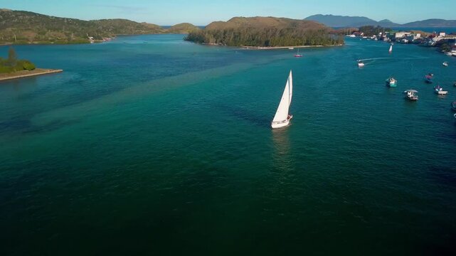 Aerial view of a sailboat cruising the blue waters of Cabo Frio, with surrounding boats.