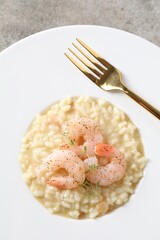 Delicious risotto with shrimps and cheese on grey table, top view
