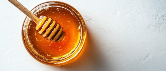 Topdown view of a honey jar with a wooden dipper, set against a white background, providing a clean layout for branding and marketing content
