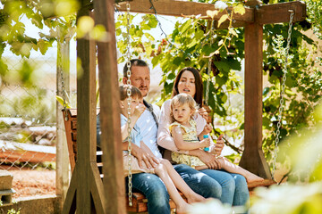 Relax, swing and parents with kids in garden for bonding, happy relationship and outdoors together. Backyard, family and mom, dad and children on bench for fresh air, fun and peace on weekend