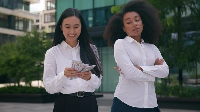Asian Korean African American women count money salary bonus income envy arms crossed females inequality business financial colleague rivalry jealousy cash pay bills discrimination girls rich outdoors