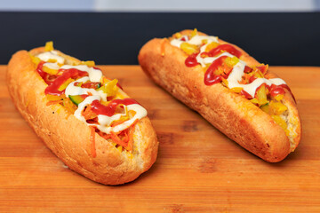 Two hot dogs with mustard and ketchup on wooden table
