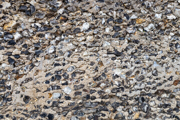 Full frame abstract texture background of a rustic medieval flint and mortar stone wall
