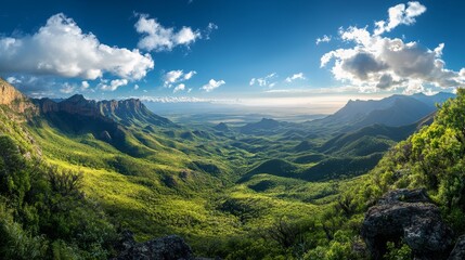 Panoramic view of a valley with mountains in the background and a blue sky with white clouds.