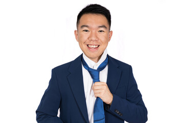 A young man in a suit is smiling while adjusting his tie