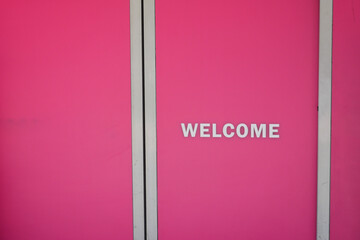 A striking bright pink wall that features a charming and warm Welcome sign present