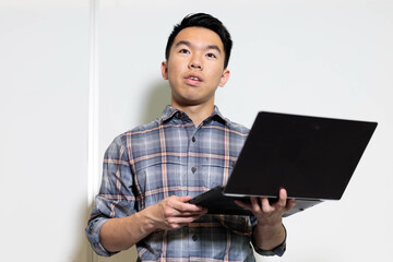 Closeup of a student giving a presentation with his laptop in front of the classroom