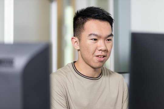 Closeup of a man student sitting in front of computer monitors - Powered by Adobe