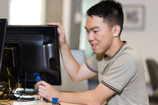 A college student is working on fixing a computer monitor