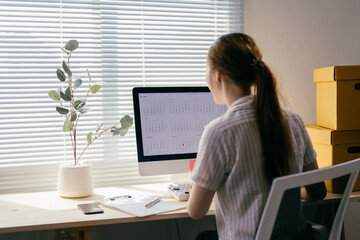 Businesswoman is sitting at her desk and looking at a calendar on her computer screen, she's...