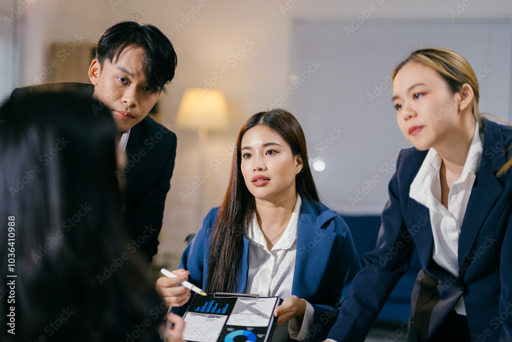 Poster team of asian professionals are engaged in a discussion, analyzing financial data presented on chart