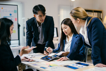 Team of young professionals are discussing business strategy and analyzing financial data on a digital tablet in a modern office