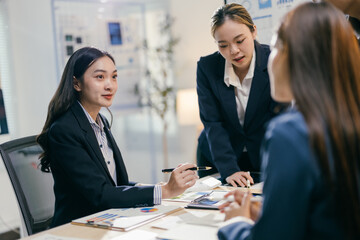 Team of asian businesswomen are having a meeting in a modern office, discussing financial data and using a calculator