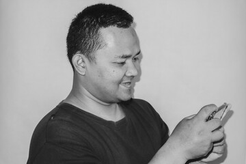 A man is smiling as he plays a game on his phone.