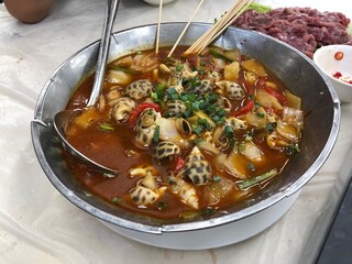 Sea snails in spicy wine sauce with tableware bamboo sticks, food stall cuisine