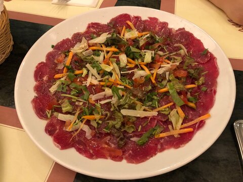 Traditional beef carpaccio with cheese and salad on ceramic plate, raw meet, Italian cuisine
