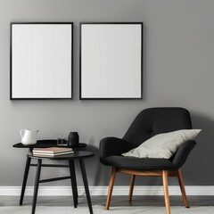 In a modern gray interior, two black-framed blank canvases hang above a sleek black table with books, decorative items, and a cozy chair, creating a chic environment.
