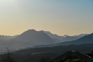 Obraz premium Scenic sunset view of silhouette mountain range Bleiberger Erzberg in Gailtal Alps seen from Sternberg, Wernberg, Carinthia, Austria. Valley covered by idyllic forest, Austrian Alps. Alpine landscape