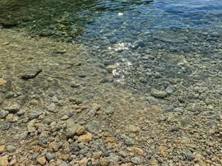 Sea clear water with pebbles and smooth stones on the shore