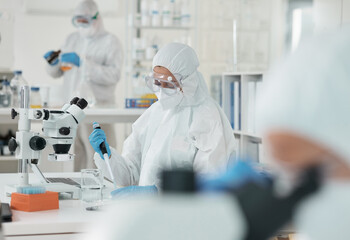 People, ppe and scientist checking virus, test results or pharmaceutical innovation with mask. Safety, gear or lab technician team at desk for bacteria research, medical danger or vaccine development