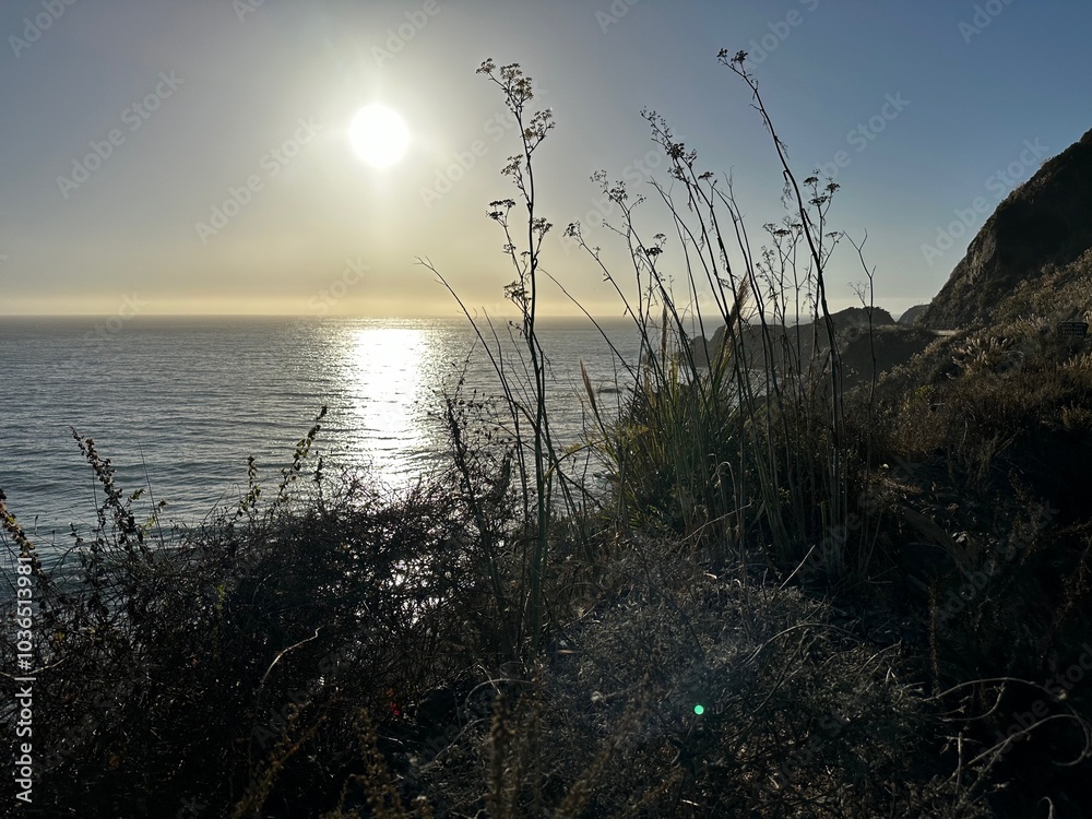 Wall mural the image shows a stunning ocean sunset with the sun low on the horizon casting a bright reflection 