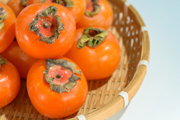 Delicious ripe persimmons in bowl on blurred background, closeup