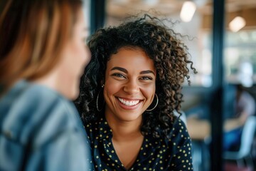 A smiling woman with curly hair looks at a friend