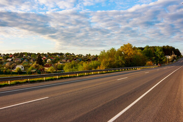 Fototapeta premium View of asphalt road with rural buildings in the background