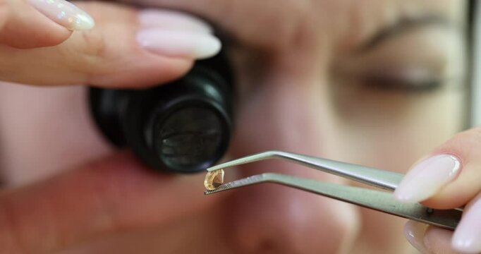 Woman uses jeweler magnifier tool examining small diamond