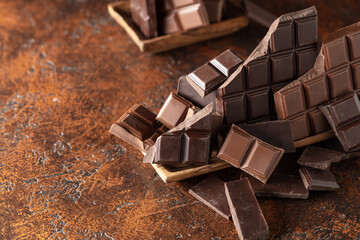 Broken bitter and milk chocolate bars on a brown background.